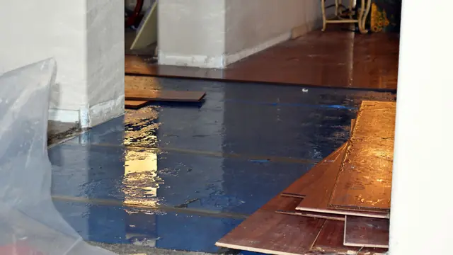 Hardwood floor boards lifted and covered with plastic sheeting after water damage
